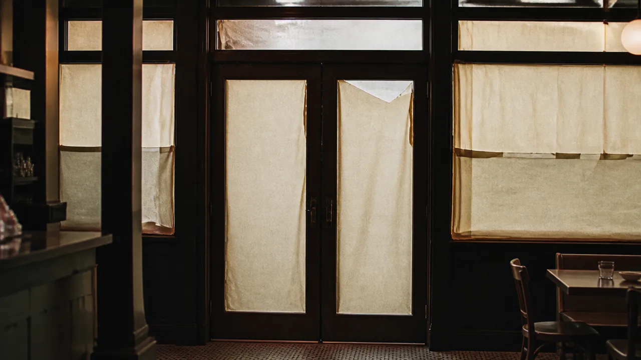 Front door of a restaurant with paper still covering the glass, from inside